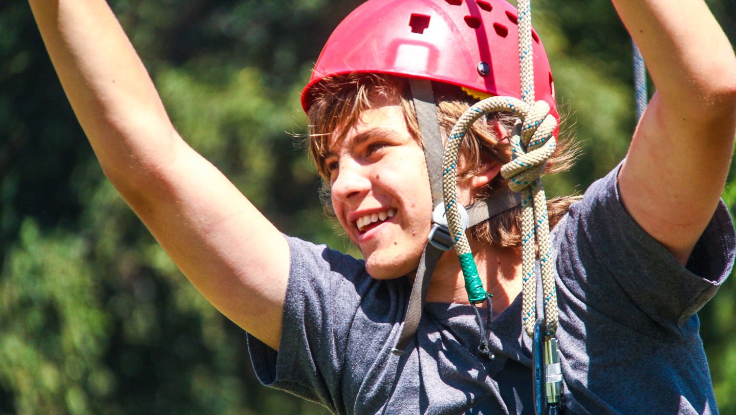 A camper smiling while on a zipline.