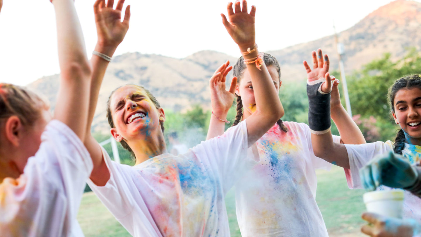 Campers with their hands in the air laughing and smiling.